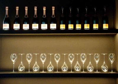 Eine Reihe Weingläser und Flaschen auf einem Regal.