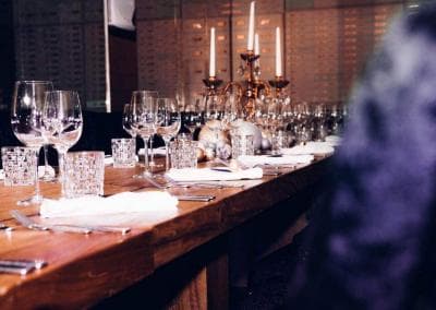 Ein langer Tisch ist mit Weingläsern und Besteck gedeckt.