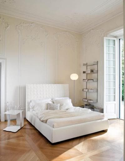 Ein weißes Schlafzimmer mit Holzböden und einem weißen Bett.