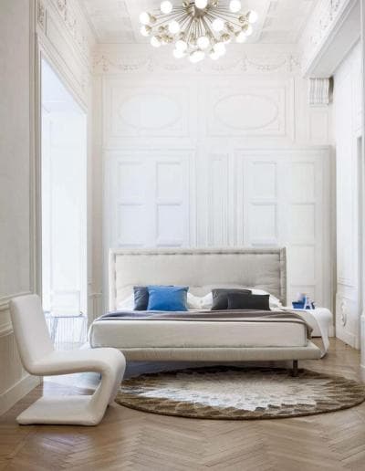 Ein weißes Schlafzimmer mit Holzböden und einem Kronleuchter.