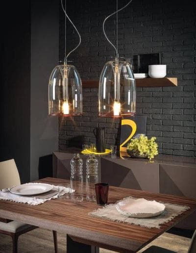Ein Esszimmer mit zwei Glaspendelleuchten, die über einem Holztisch hängen.